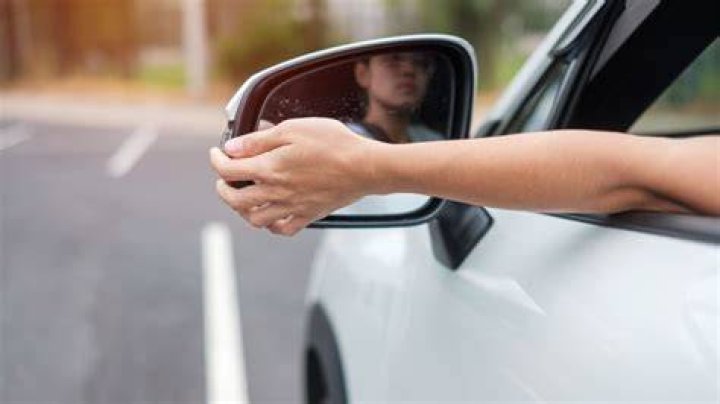 When adjusting the driver side side mirror you should?